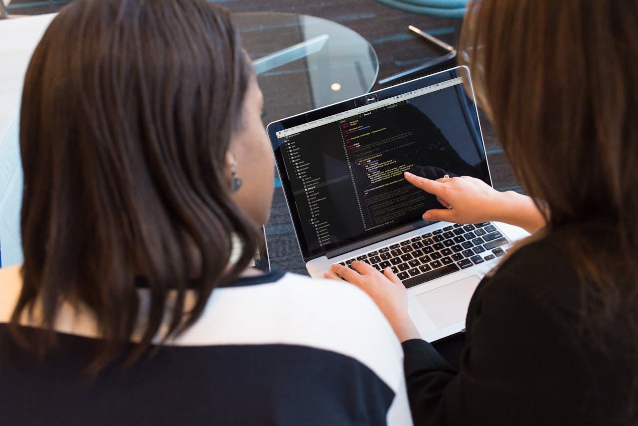 gallery-2 Two women working together on software programming indoors, focusing on code.